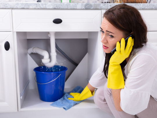 woman calling an emergency plumber in garland to help with leaky pipe